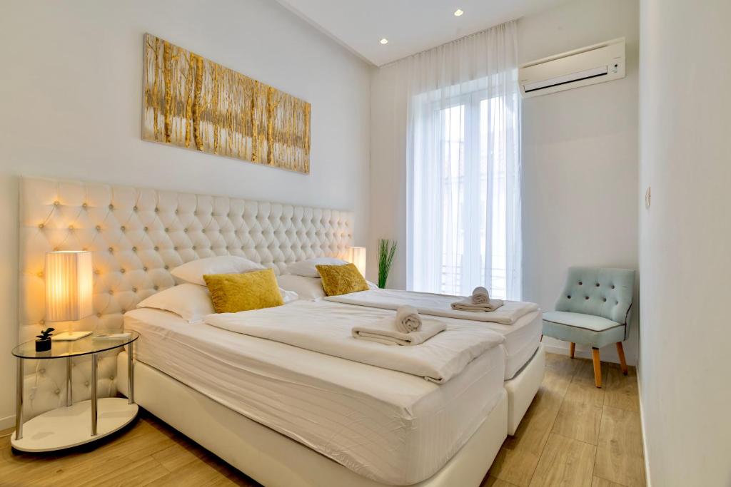 a white bedroom with a large bed and a window at Apartments & Rooms Grašo in Split