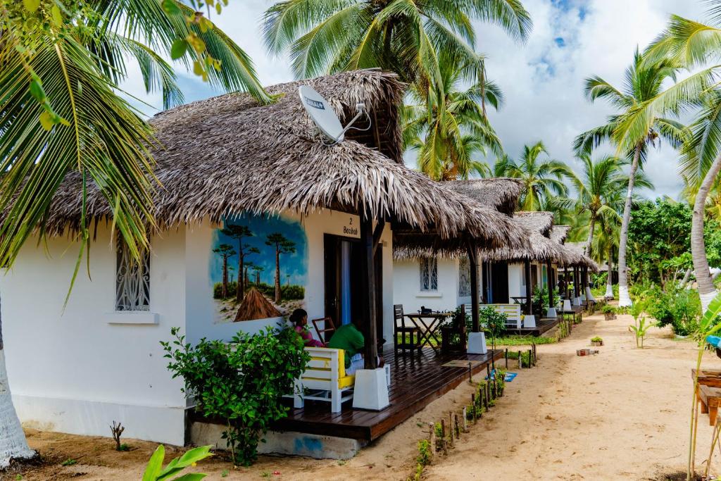 a house on the beach with palm trees at Long Beach Resort, Nosy Be in Nosy Be