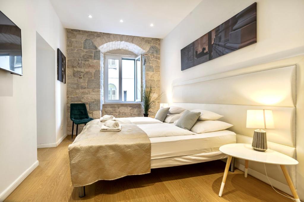 a bedroom with a large bed and a chair at Apartments & Rooms Grašo in Split
