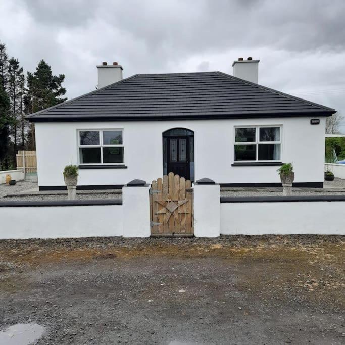 a white house with a wooden gate in front of it at Cheerful three bedroom country cottage in Ballina