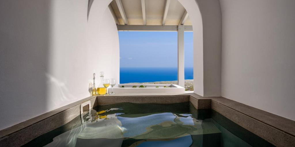 a bathroom with a bath tub and a large window at Lotus Suites in Fira