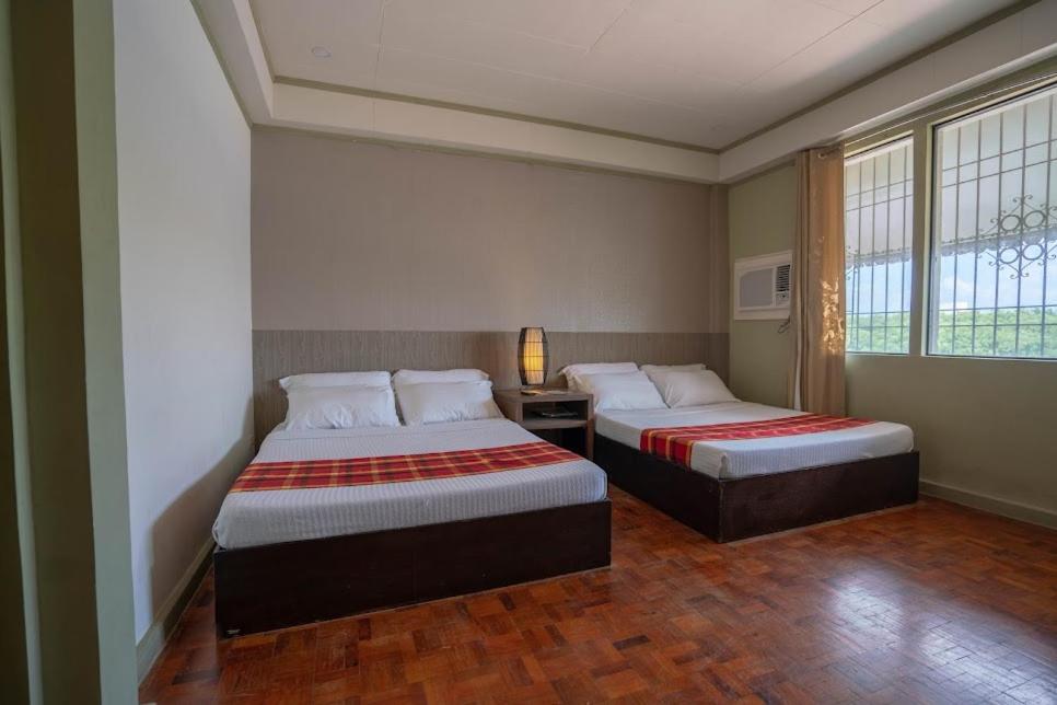 two beds in a room with two windows at Legacy Mansion + coffee bar in Iloilo City