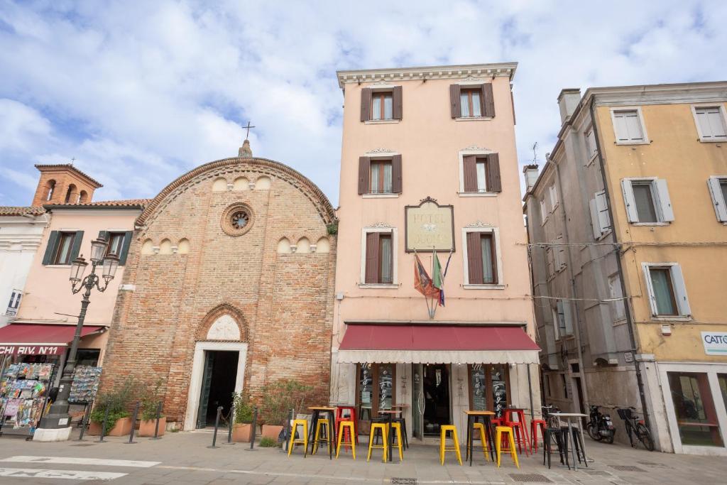 a building with tables and chairs in front of a building at Duomo Boutique Hotel in Chioggia