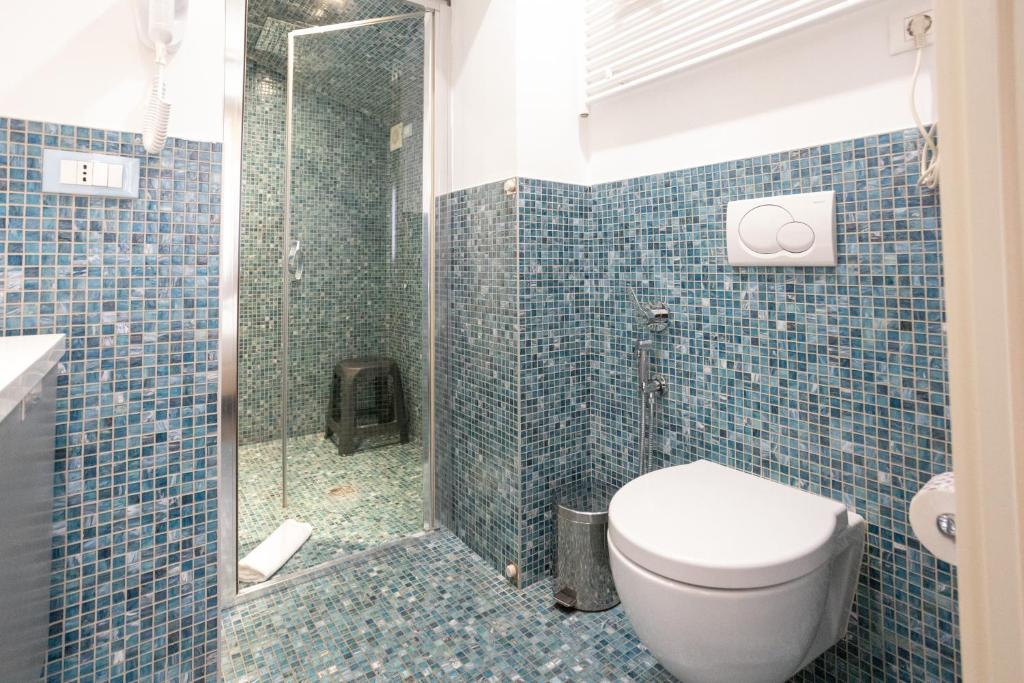 a blue tiled bathroom with a toilet and a shower at Duomo Boutique Hotel in Chioggia