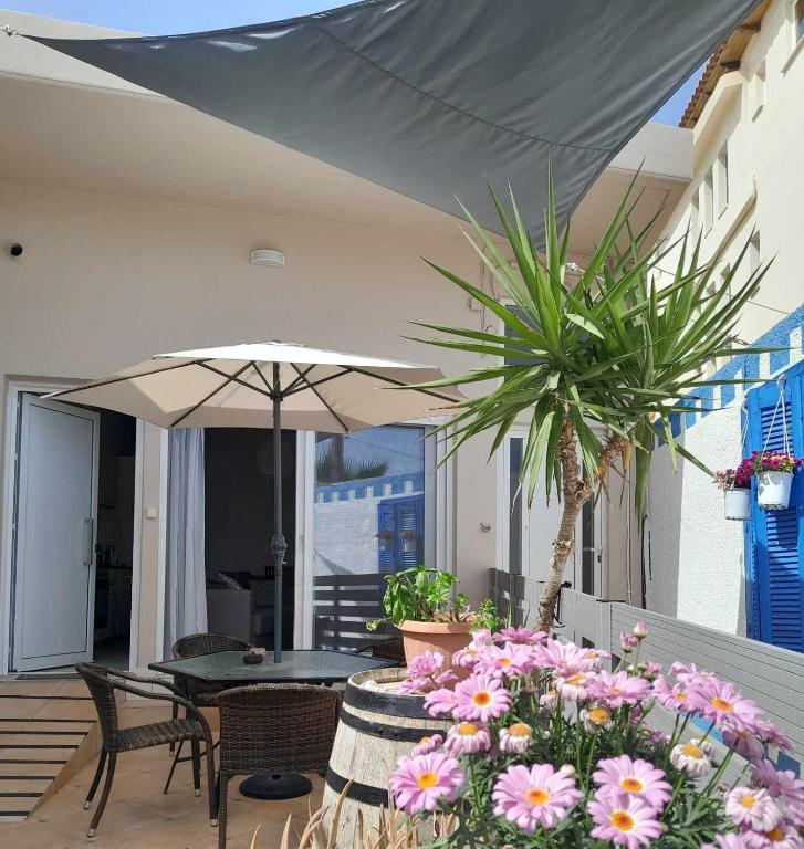 a patio with a table and umbrella and flowers at The Getaway in Agia Marina Nea Kydonias