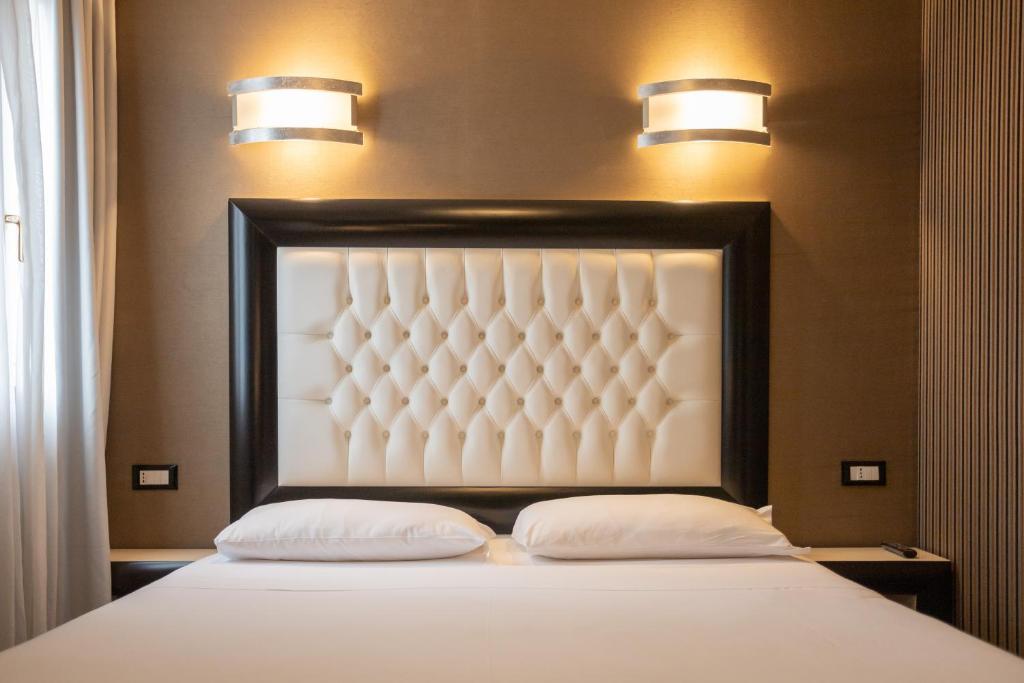 a bed with two pillows and two lights above it at Duomo Boutique Hotel in Chioggia