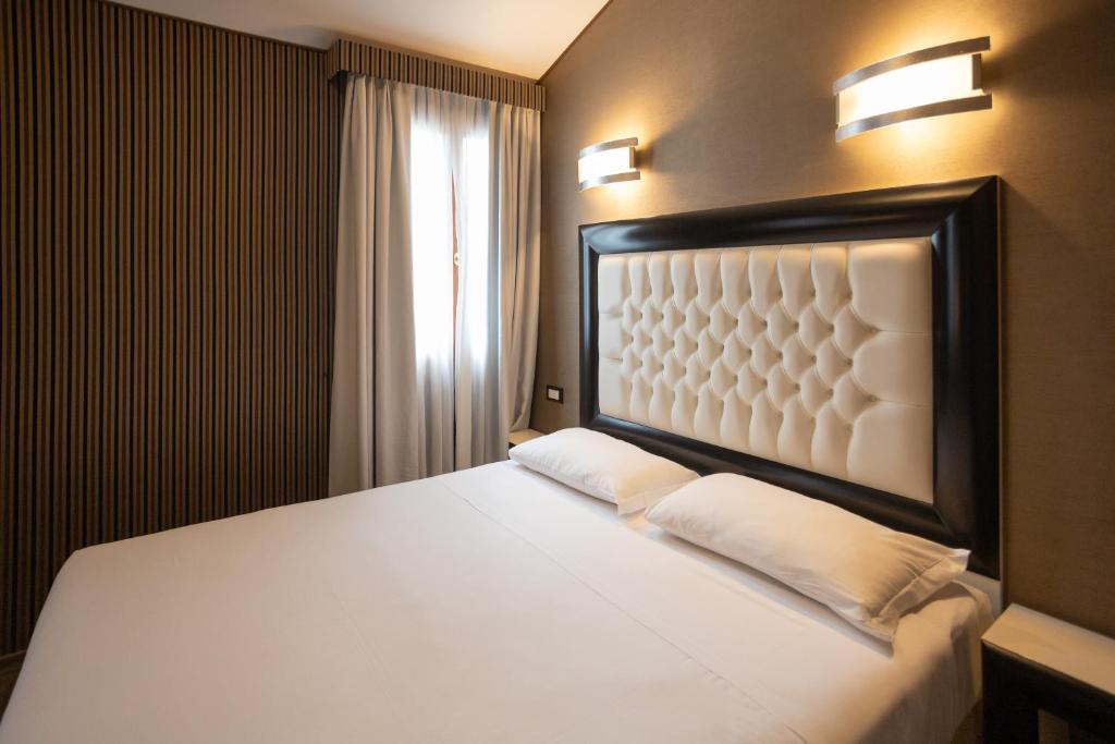 a bedroom with a large white bed with two pillows at Duomo Boutique Hotel in Chioggia