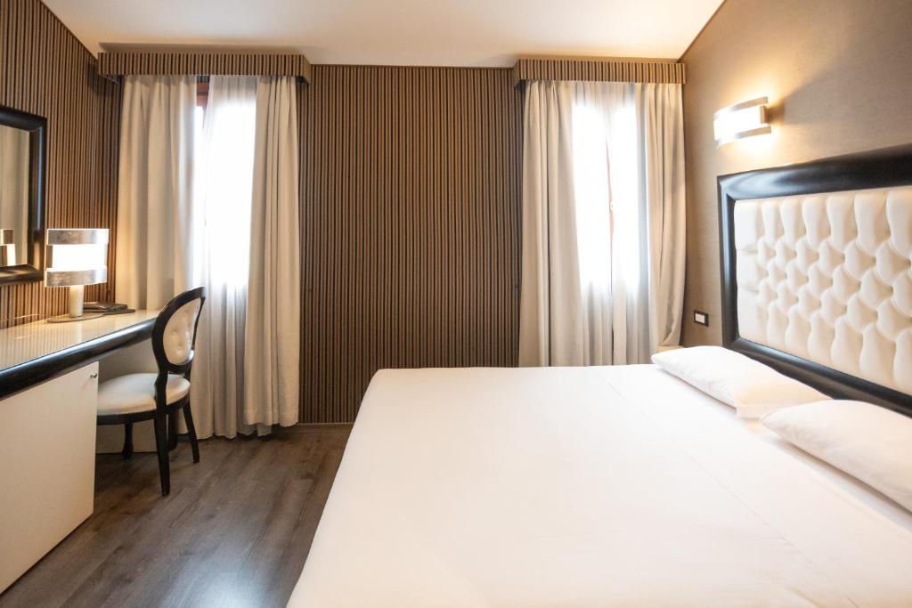 a hotel room with a large bed and a desk at Duomo Boutique Hotel in Chioggia