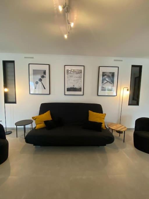 - un salon avec un canapé noir et 2 tables dans l'établissement Rez de jardin vue mer, à Marseille