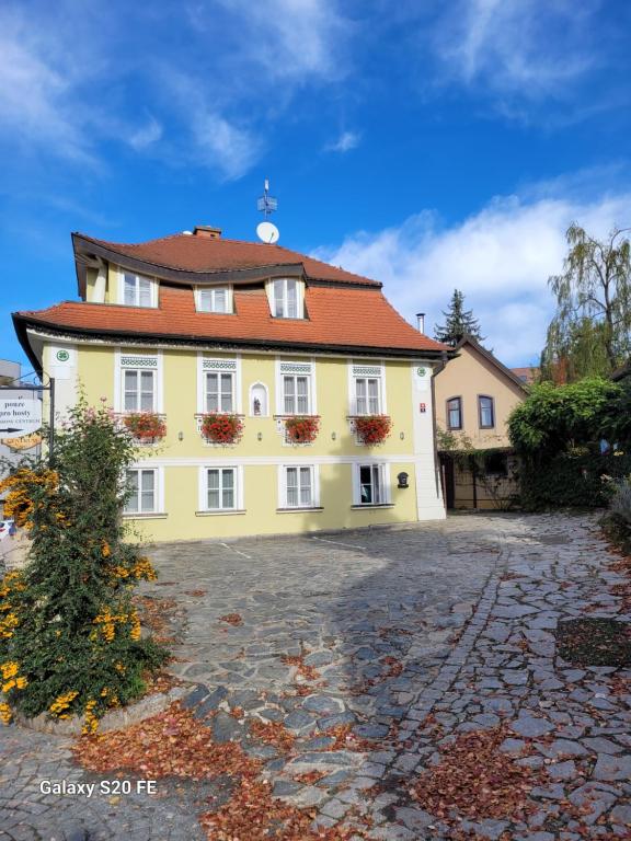 a large yellow house with a red roof at Pension Centrum in Ricany