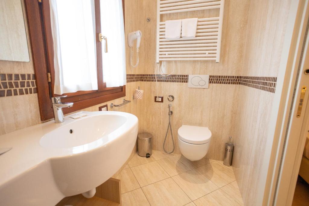 a bathroom with a white sink and a toilet at Duomo Boutique Hotel in Chioggia