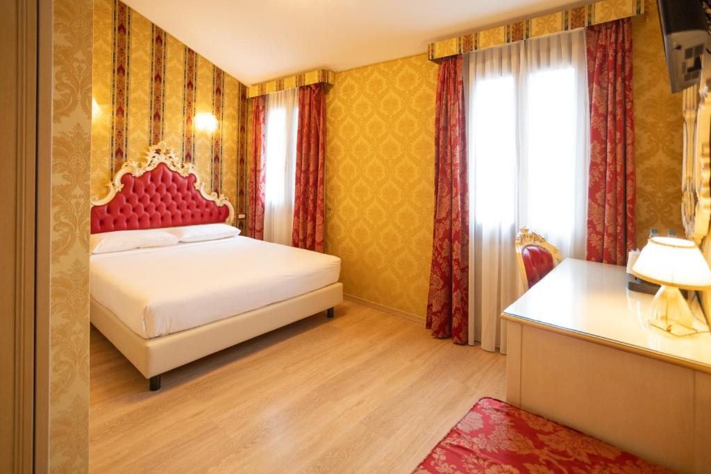 a bedroom with a bed with a red headboard and a window at Duomo Boutique Hotel in Chioggia