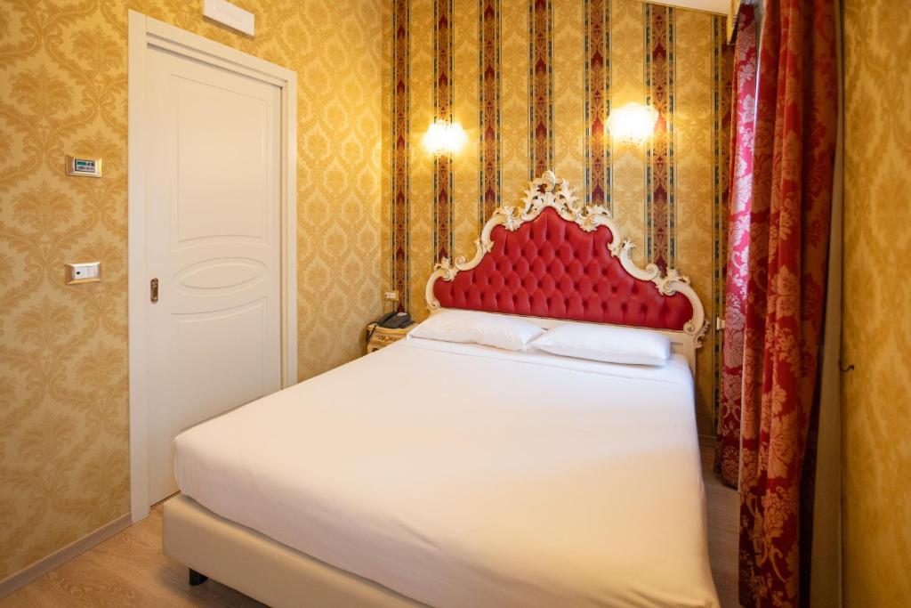 a bedroom with a white bed with a red headboard at Duomo Boutique Hotel in Chioggia