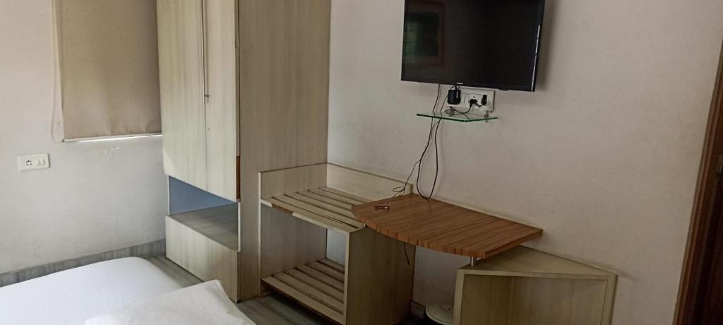 een kleine kamer met een bureau en een tv aan de muur bij Ballygunge Guest House in Calcutta