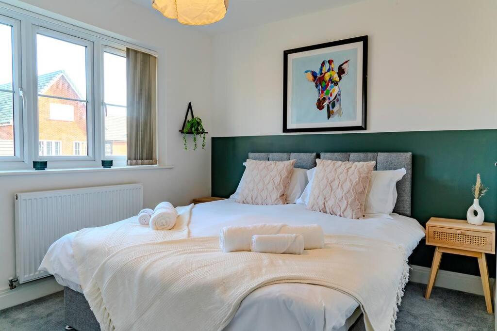 a large white bed in a room with windows at Idyllic 3-bed home in Peterborough with Parking by HP Accommodation in Peterborough