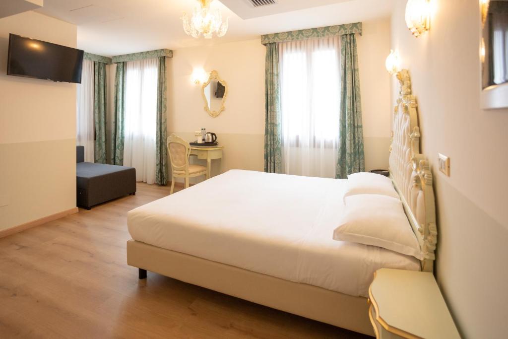 a bedroom with a large bed and a table at Duomo Boutique Hotel in Chioggia