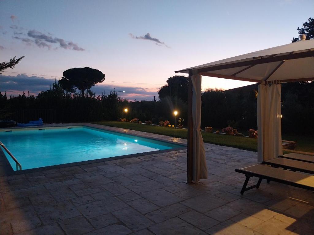 a swimming pool with an umbrella and a bench at La casa di Tommy in Cortona