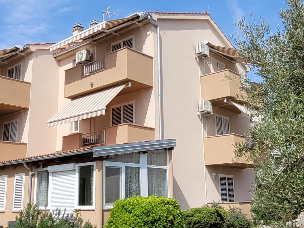 an apartment building with balconies and trees at Rooms Magdalena Krk in Krk