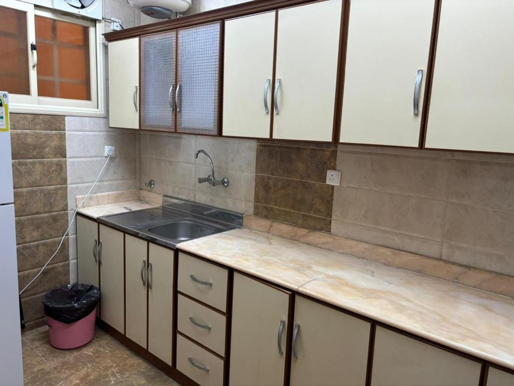 a kitchen with white cabinets and a sink at قصر نوماس للشقق المخدومة الواديين in Al Wadeen