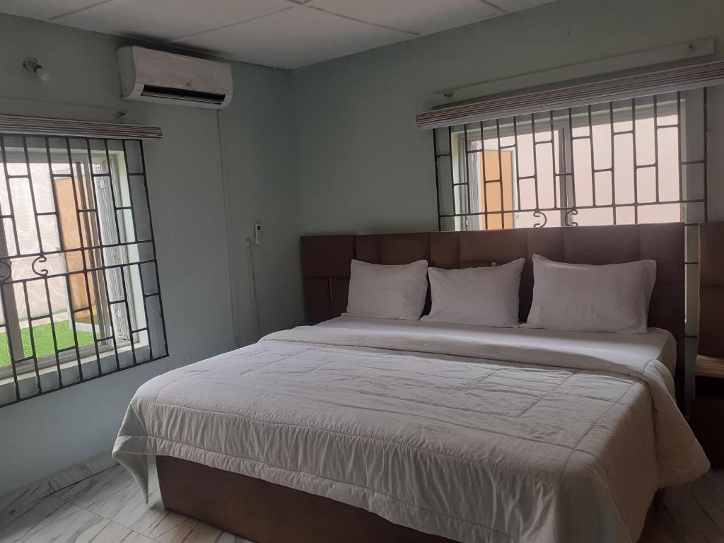 a bedroom with a large bed with two windows at Biddex Lodge & Hotels in Benin City