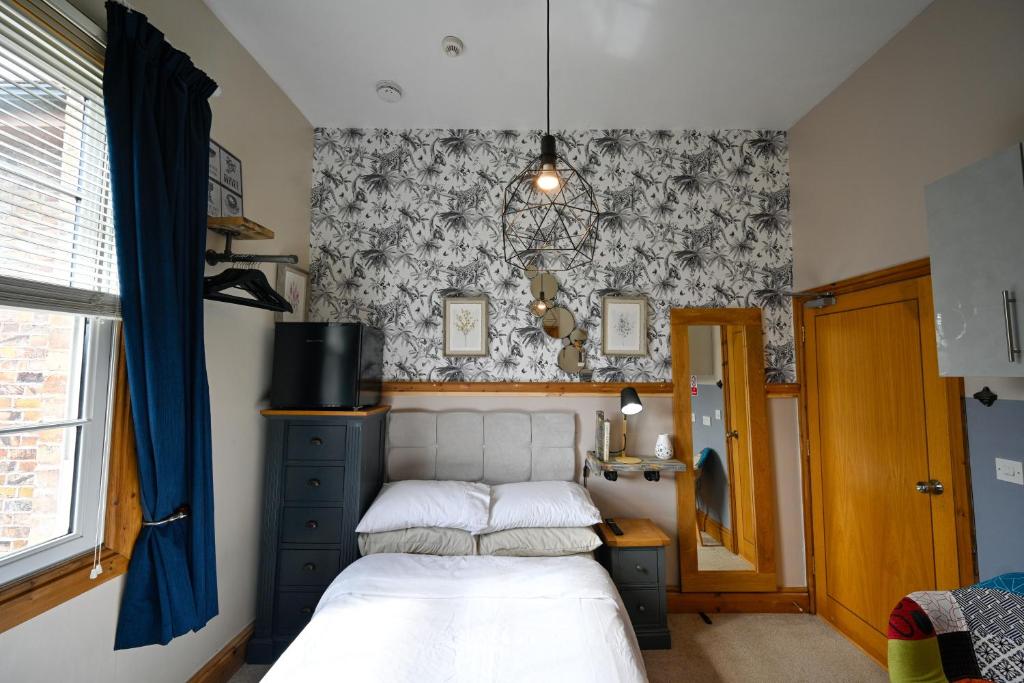 a bedroom with a bed and a wall with a wallpaper at Cherry Tree Studio in Telford