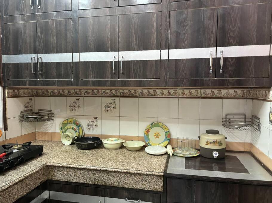 uma cozinha com armários de madeira e pratos no balcão em Entire House- Ground Floor- Raj Villa em Kanpur