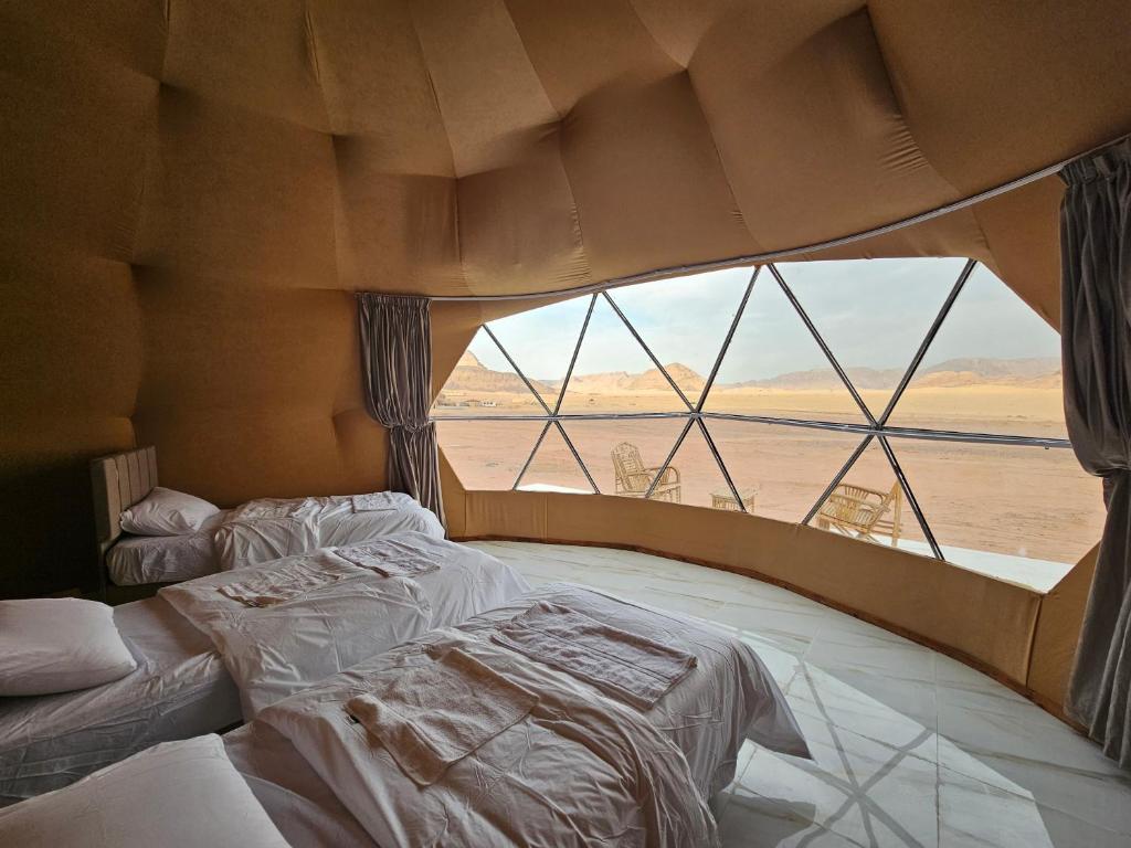 a room with two beds and a large window at Kylie magic camp in Wadi Rum