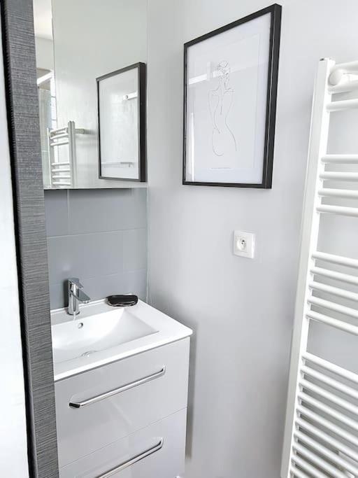 a white bathroom with a sink and a mirror at Le Raphaëlle - Compiègne centre in Compiègne
