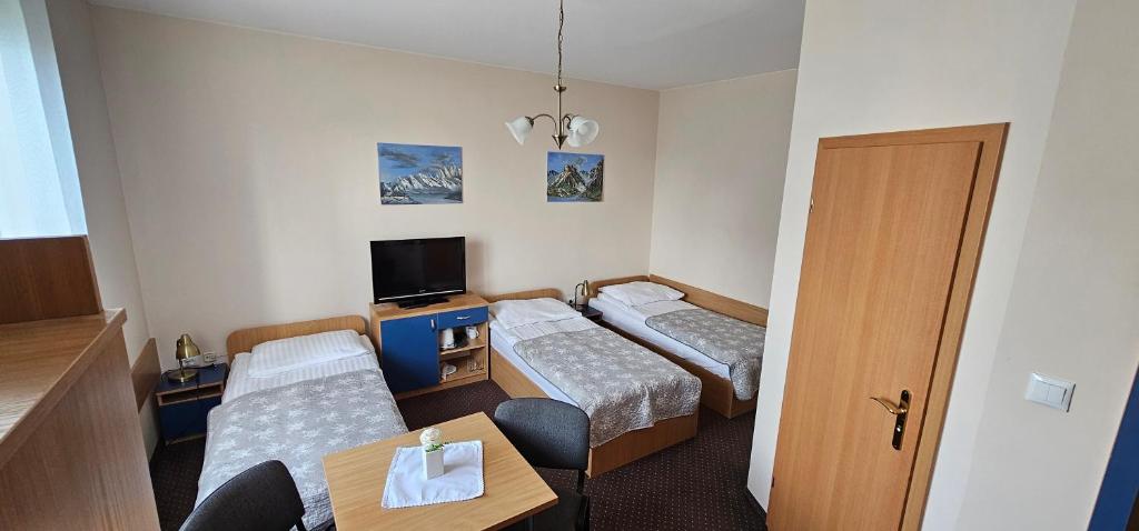 Una habitación de hotel con dos camas y un televisor. en Hotelik u Sąsiada, en Olsztyn