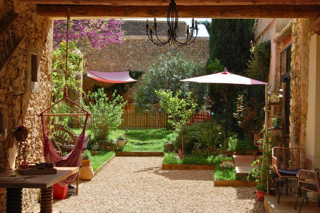 un patio al aire libre con mesa y sombrilla en La Bucolique, Chambres et Jardin d'Hôtes en Sabran