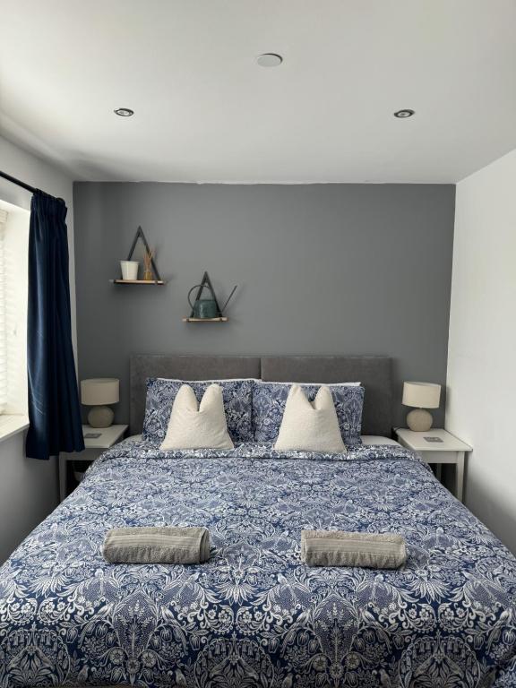 a bedroom with a blue bed with two pillows on it at Abbey’s Inn in Cheadle