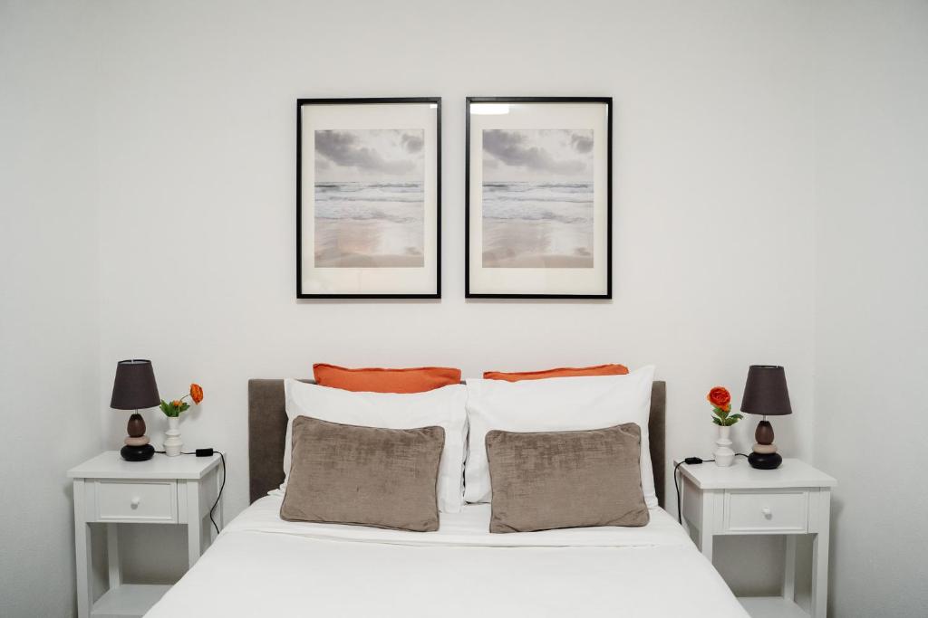 een witte slaapkamer met drie foto's boven een bed bij Porto Ribeira RC Traseiras in Porto