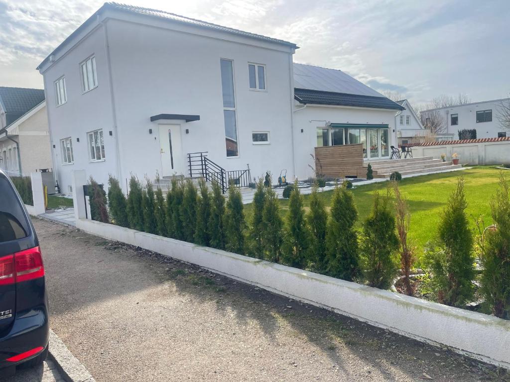 a white house with a row of trees in front of it at New flat in Limhamn in Limhamn
