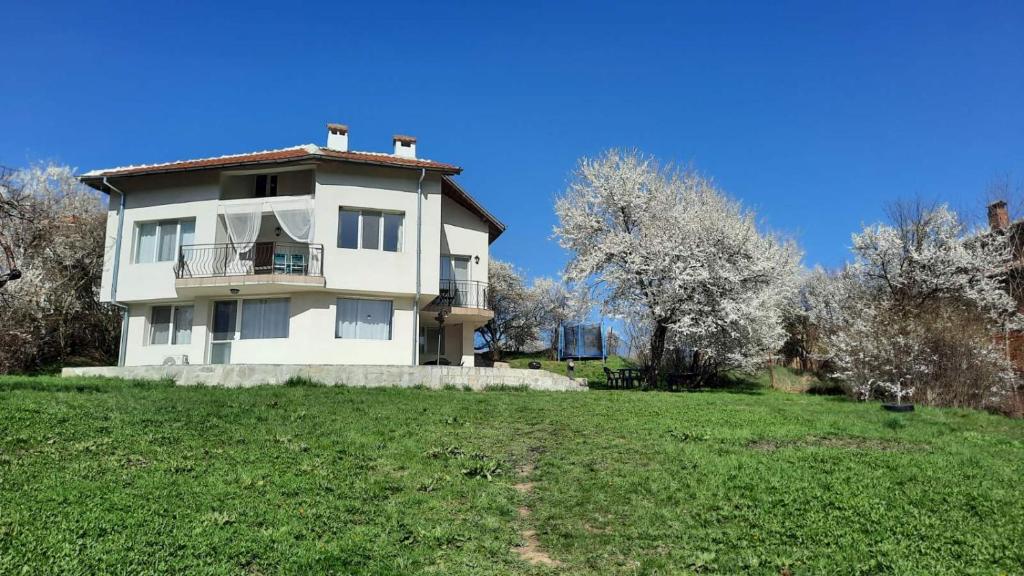 a white house on top of a green field at "House of swallows" vacation home, close to Sofia in Makotsevo