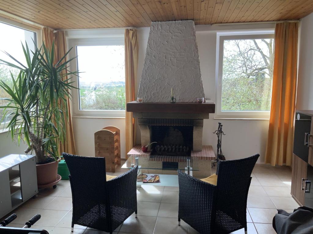 - un salon avec une cheminée, une table et des chaises dans l'établissement Ferienwohnung Brenda, à Schillingsfürst