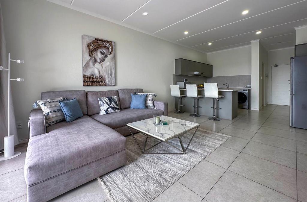 a living room with a couch and a table at StayEasy Lux Apartment in Edenvale