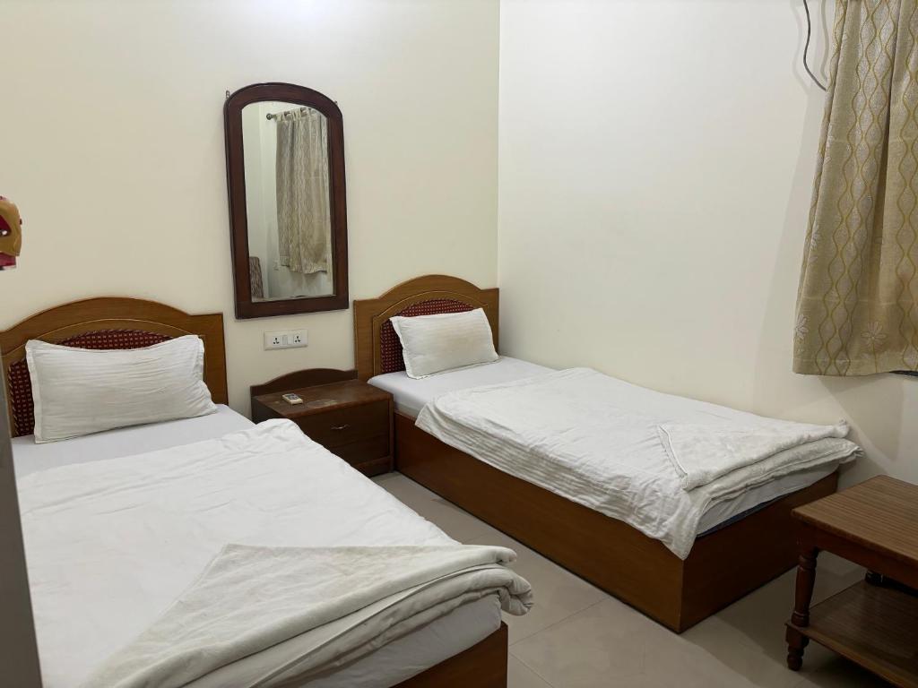 2 camas en una habitación pequeña con espejo en Lucky Guest House Bodhgaya, en Bodh Gaya