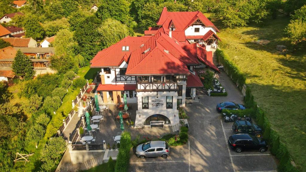 ein großes Haus mit Autos auf einem Parkplatz in der Unterkunft Conacul Bratescu in Bran
