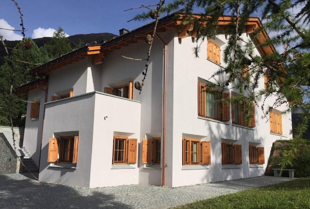 Cette maison blanche dispose de portes et de fenêtres en bois. dans l'établissement Aroevens, à Pontresina