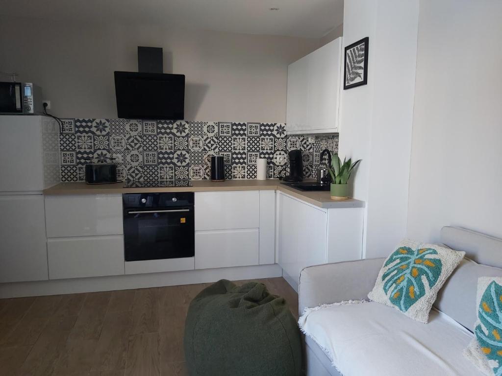 un salon avec un canapé et une cuisine dans l'établissement Maisonnette proche mer 4 pers, à Courseulles-sur-Mer