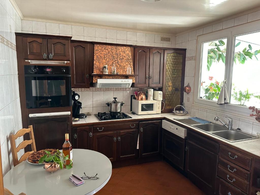 a kitchen with wooden cabinets and a sink and a table at Villa martin in Antony