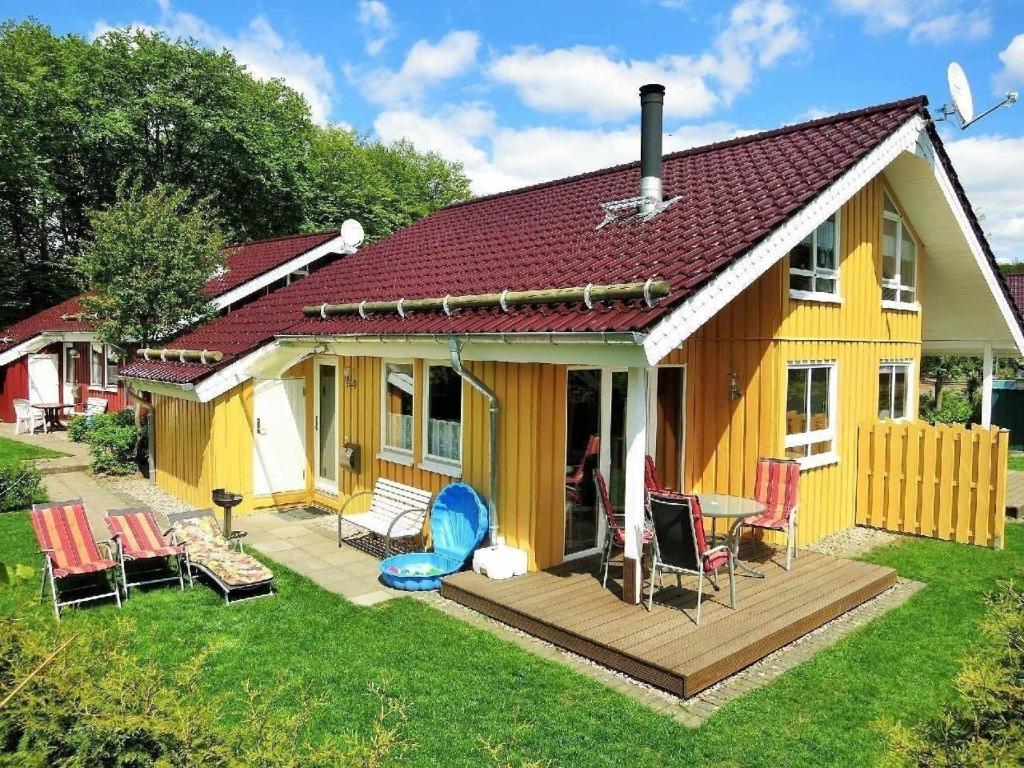a yellow house with a deck and chairs at Gemütliches Ferienhaus Alissa für 5 Personen mit Sauna und Kaminofen von Privat im Ferienpark Extert in Extertal