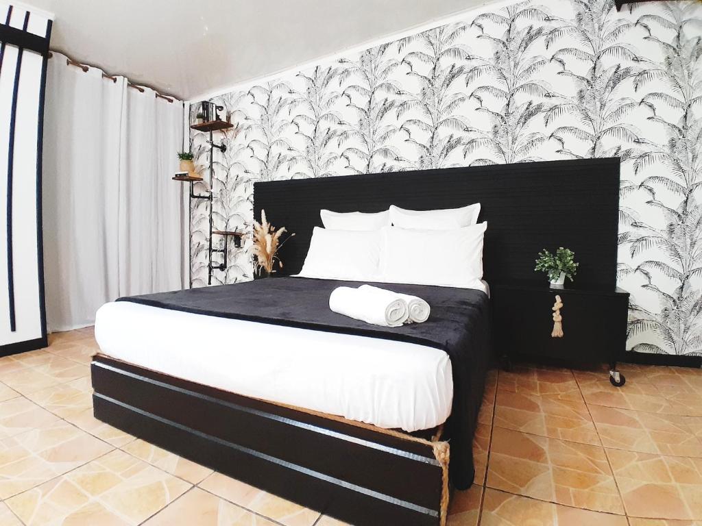 a bedroom with a bed with a black and white wallpaper at The Secret Motel 7 Salazie à 15 min d'hell bourg in Salazie