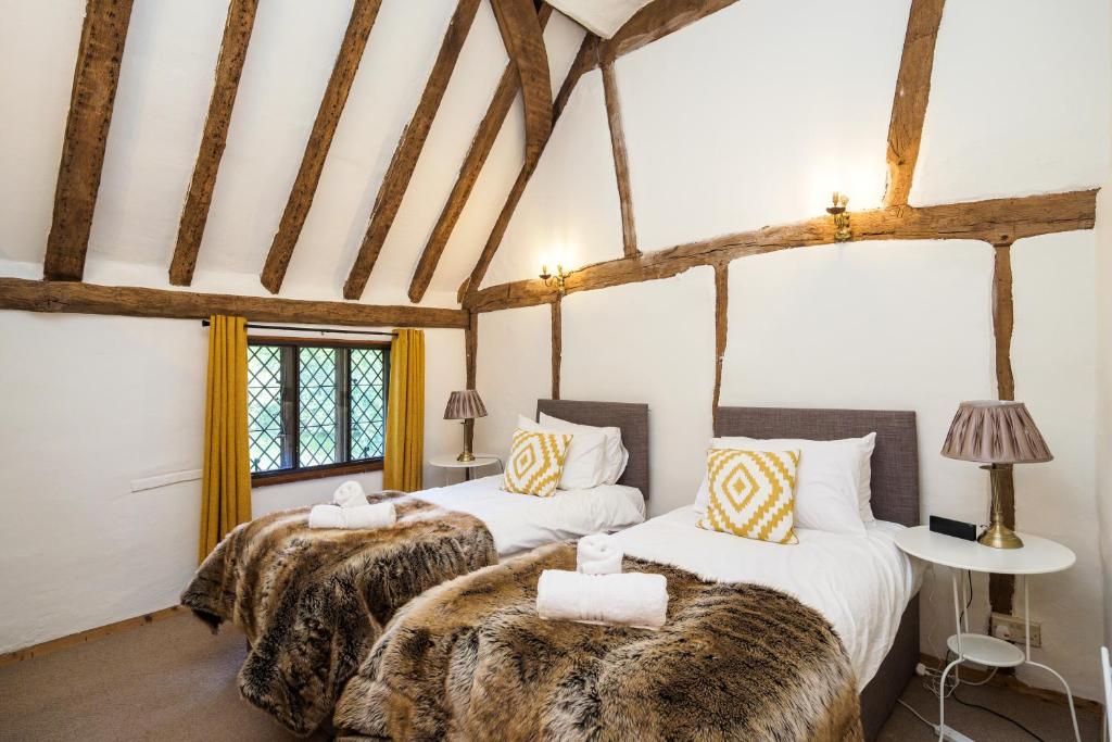two beds in a room with white walls and wooden beams at Gildridge in Chiddingly