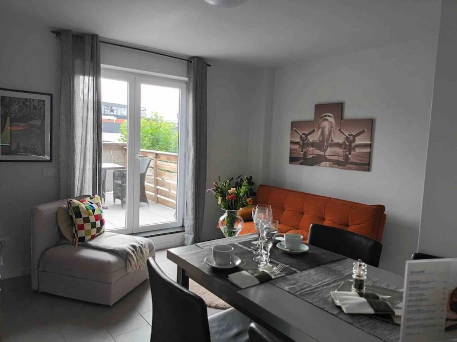 een woonkamer met een oranje bank en een tafel bij Appartamento confortevole in Deinze