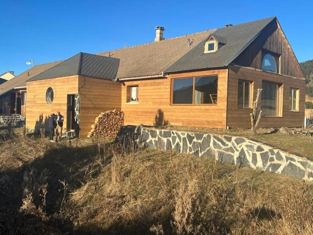 une maison en bois sur une colline avec un mur en pierre dans l'établissement GÎTE AU PIED PISTES LA QUILLANE, à La Llagonne