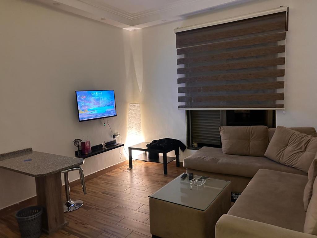 sala de estar con sofá y TV de pantalla plana en AMT, en Amán