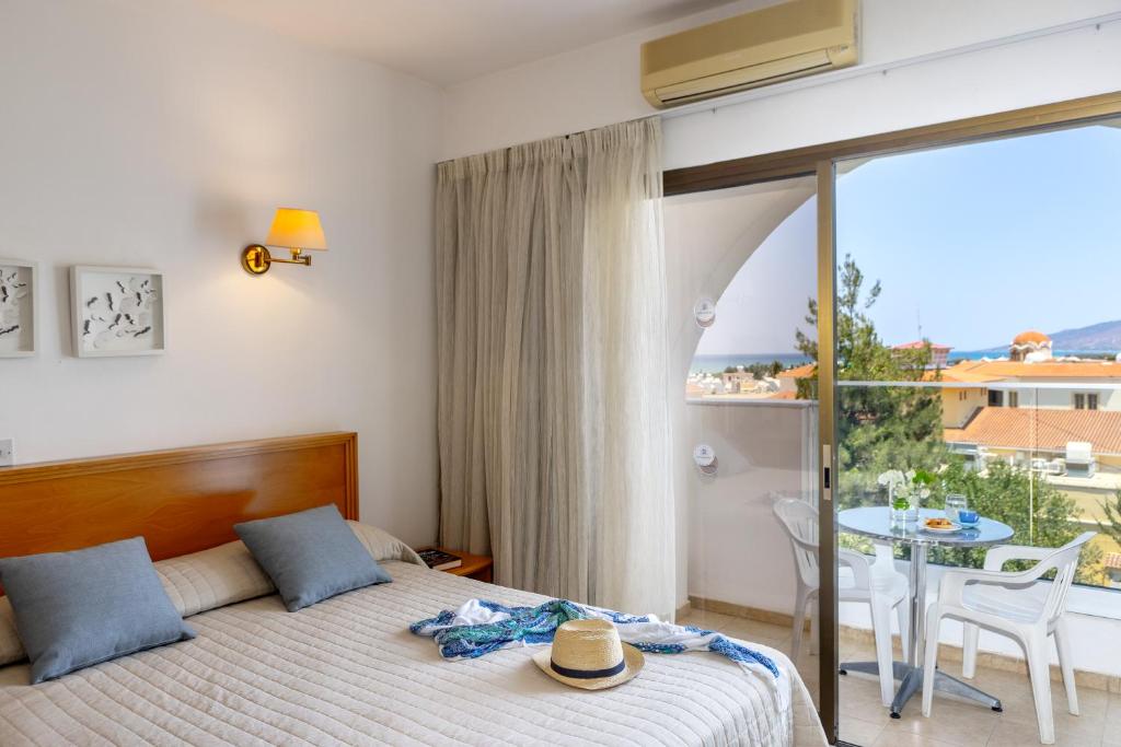 a bedroom with a bed and a balcony with a table at Stephanos Hotel Apartments in Polis Chrysochous
