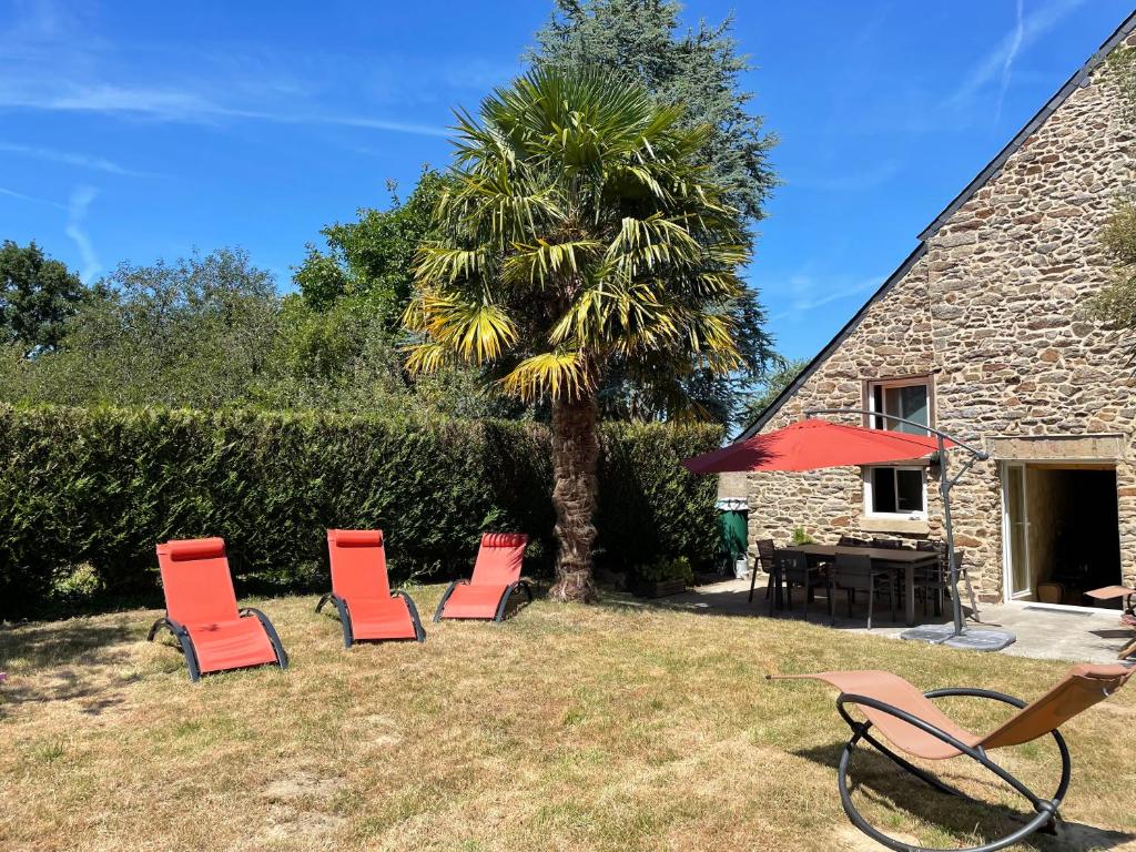 a group of chairs and a table and a palm tree at Charmante maison en bord de Rance in Plouër-sur-Rance