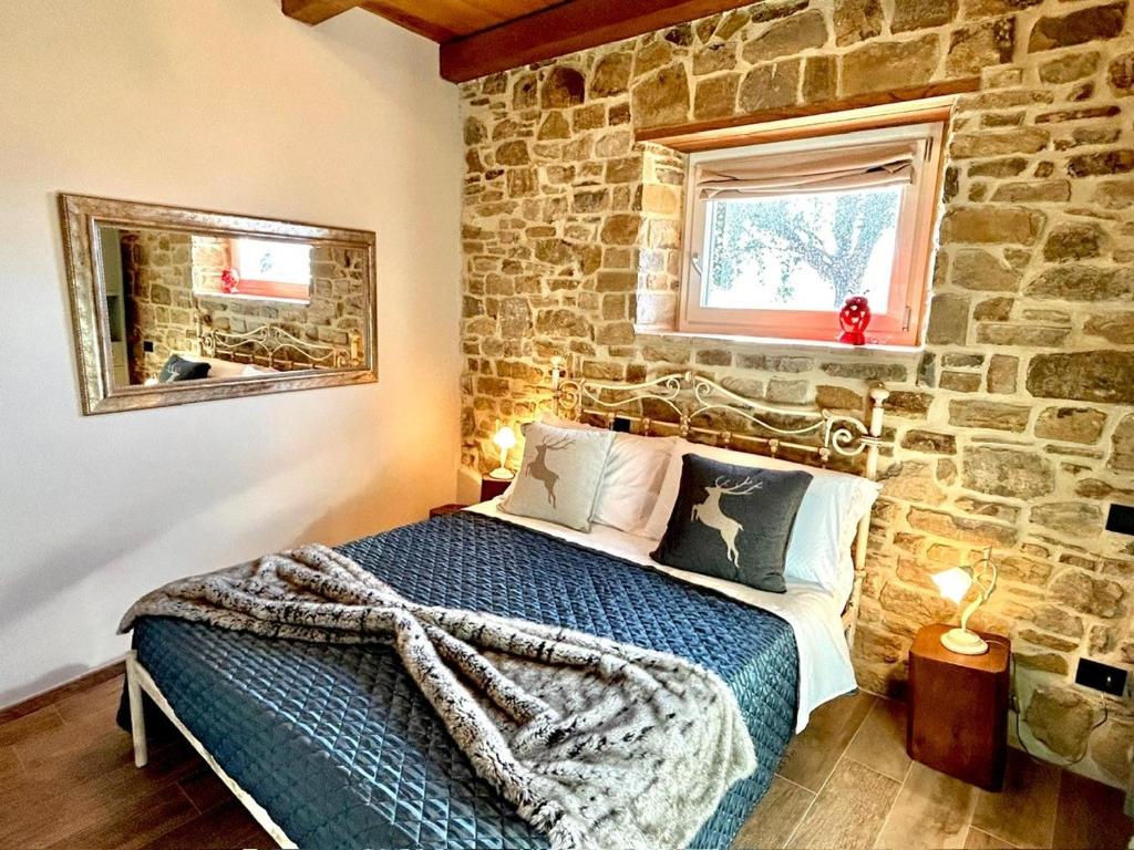 a bedroom with a bed with a stone wall at Villa Lux Poggelleri vista unica sul Casentino in Poppi
